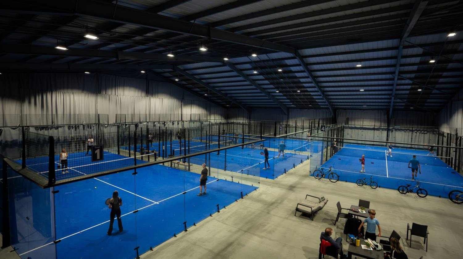 Five indoor panoramic padel courts under floodlights