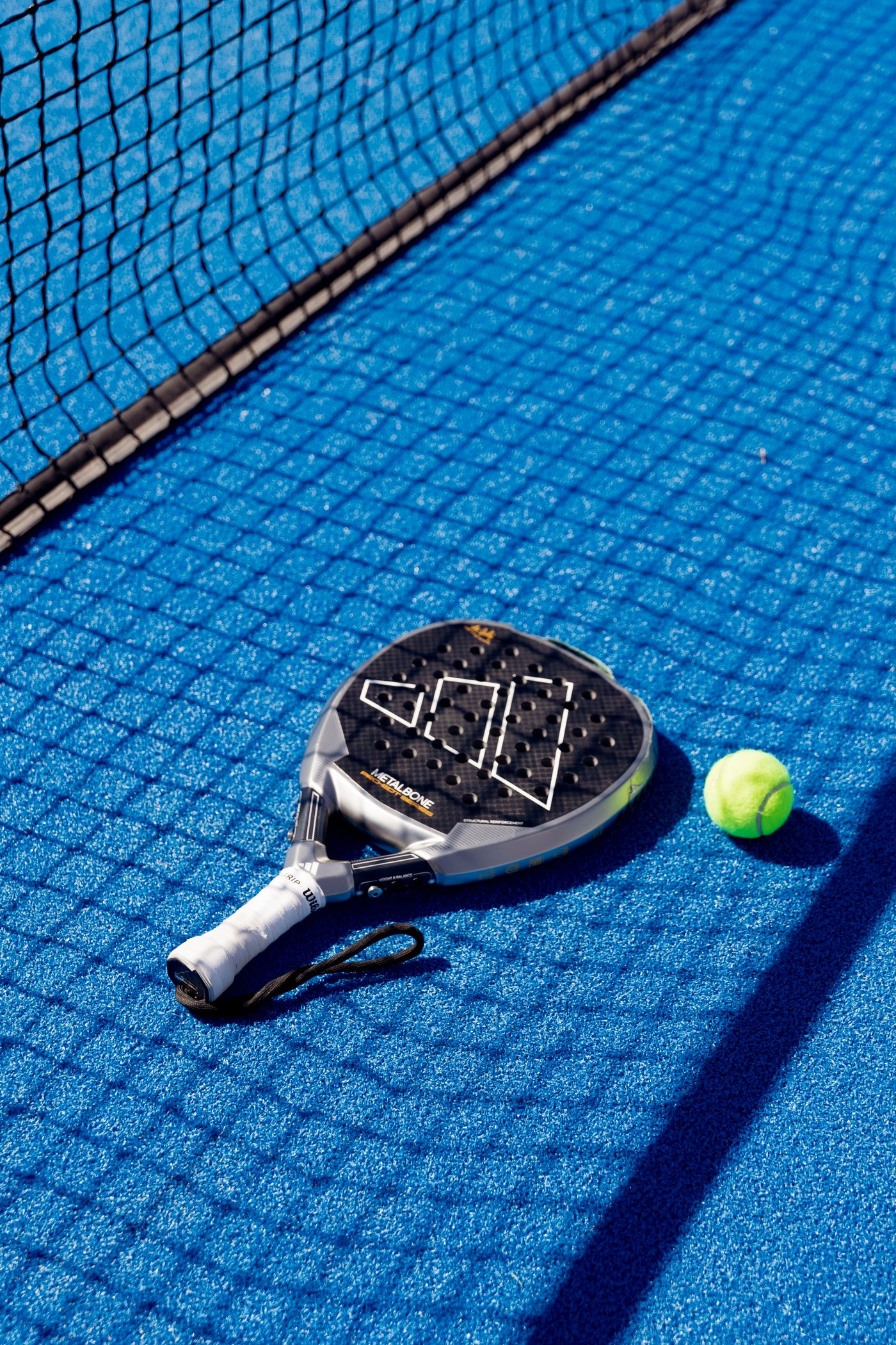 A padel racket and ball on court